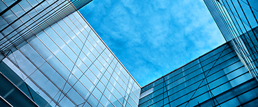 Looking up at a gap of blue sky between two modern glass buildings