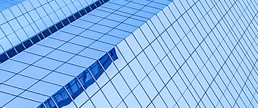 Angular glass facade of a skyscraper reflecting the blue sky